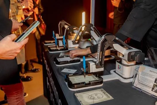 Guests filming robotic arms drawing portrait sketches at a brand activation