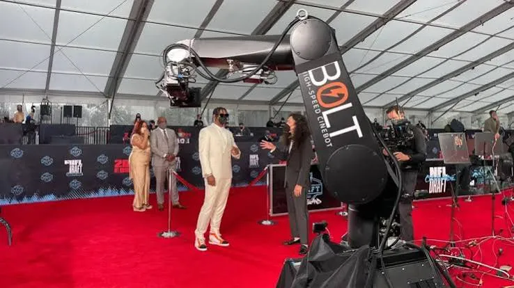 Robotic camera arm filming guests on a red carpet at a large event