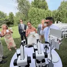 Wedding guests gathered around robotic sketch arms at an outdoor reception